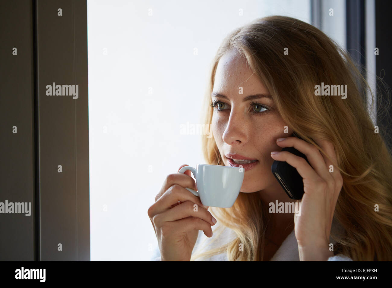Junge Frau am Telefon sprechen und trinken Kaffee Stockfoto