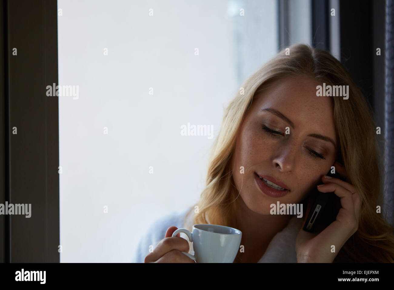 Junge Frau am Telefon sprechen und trinken Kaffee Stockfoto