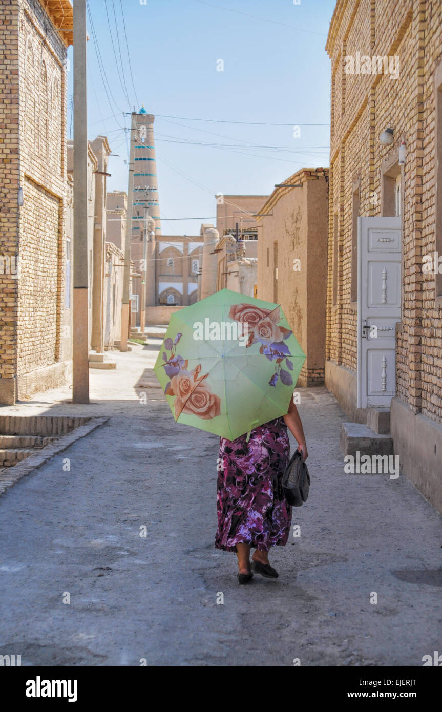 Usbekisch-Frau mit Sonnenschirm auf der schmalen Straße in Chiwa, Usbekistan Stockfoto