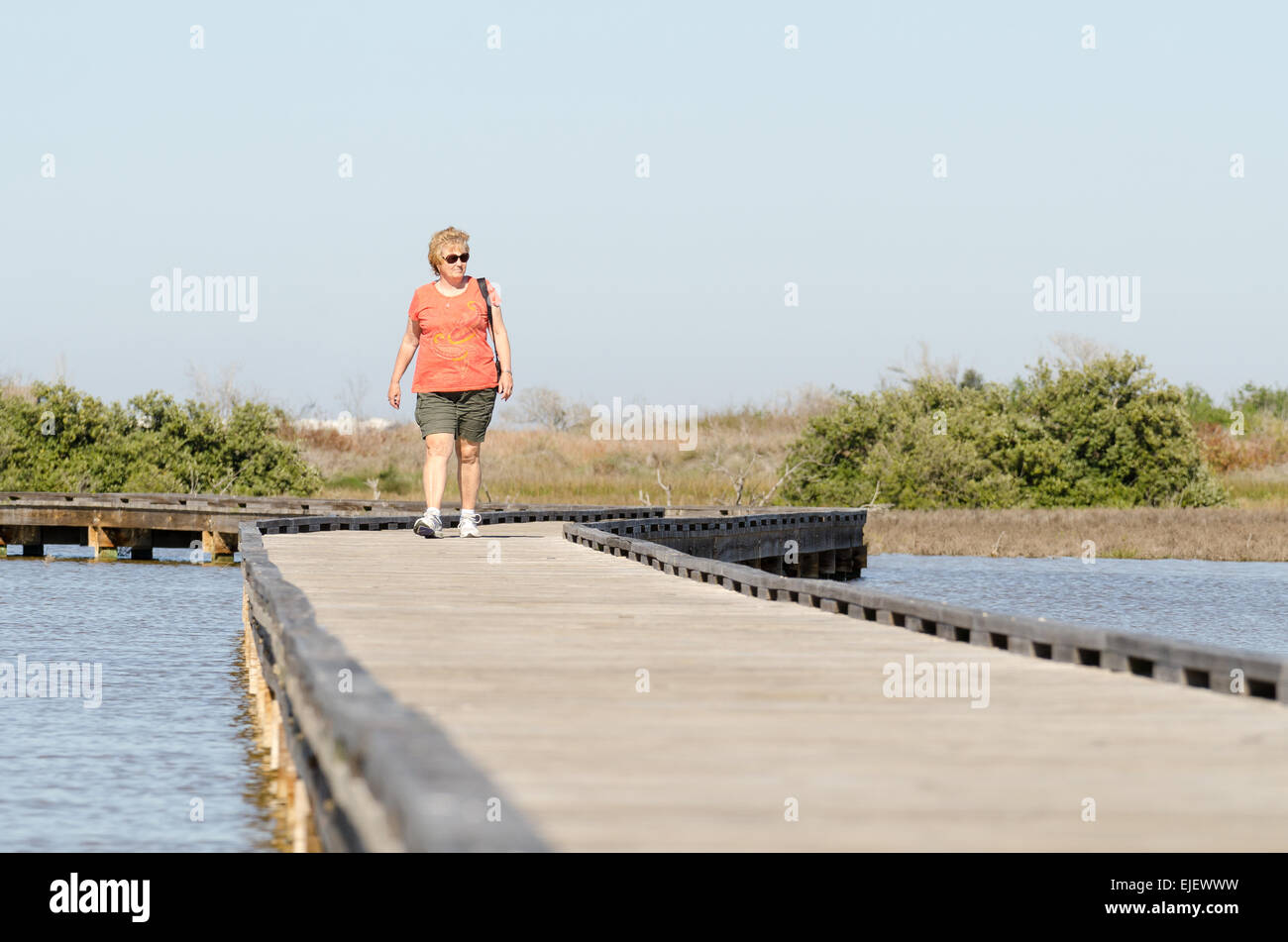 Frau in ihren 60ern zu Fuß entlang der Promenade in Charlies Weide Naturschutzgebiet in Port Aransas, Texas USA Stockfoto