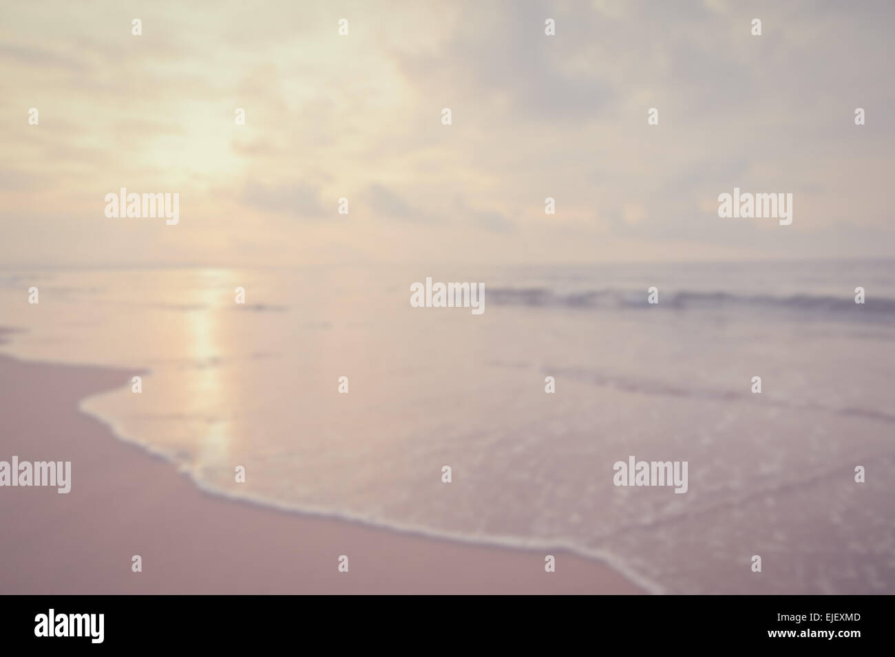 Wellen am Strand. In den Vordergrund tritt eine dünne schäumende Welle über den Sand. Sonne spiegelt sich am Meer. Stockfoto