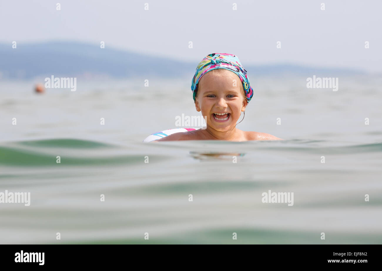 Kind schwimmt im Meer auf aufblasbaren Ring an einem klaren sonnigen Tag. Geringe Schärfentiefe. Modell im Mittelpunkt. Stockfoto