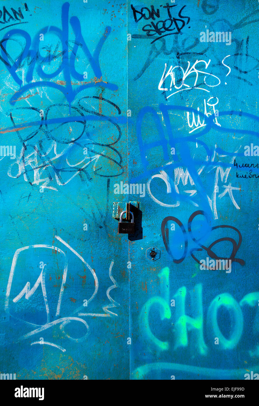 Moderne städtische Kritzeleien schmücken eine blau lackierte Tür mit einem Vorhängeschloss Stockfoto