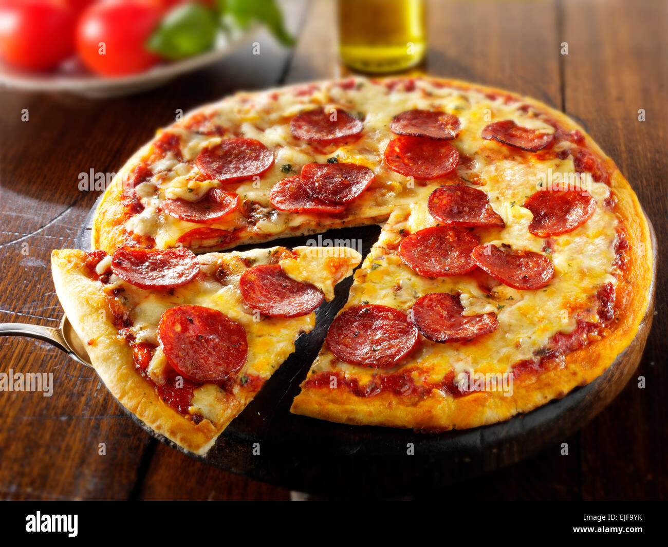 Pizza mit Salami & Käse mit einer Scheibe aus Stockfoto