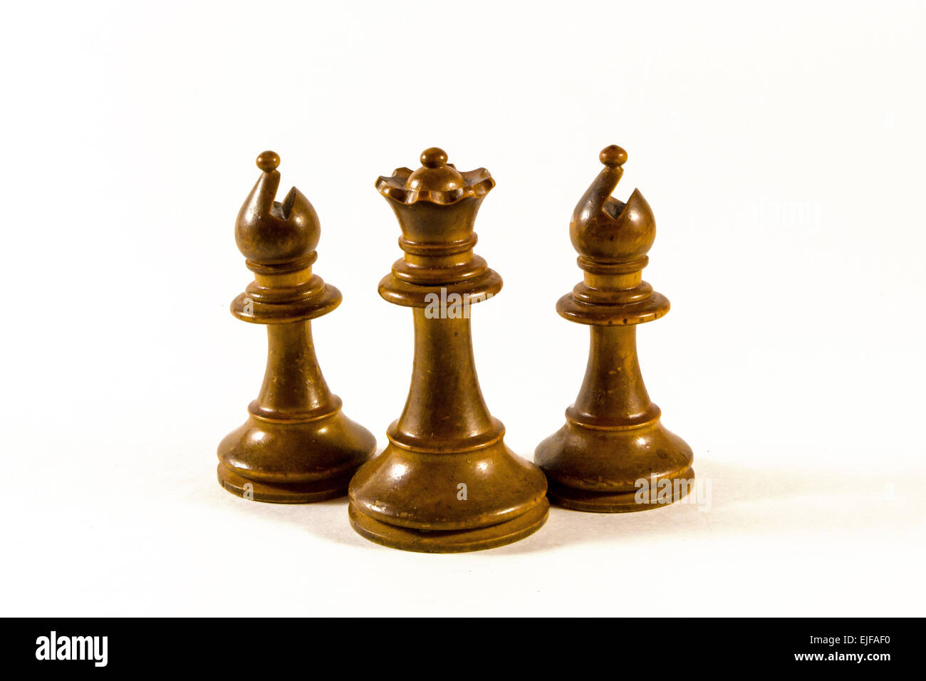 Eine hölzerne weiße Königin von Schach, flankiert von zwei Bischöfen - isoliert auf weißem Hintergrund Stockfoto