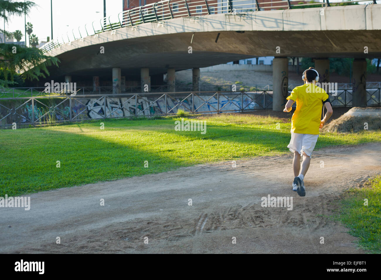 Läuft Man Joggen im Stadtpark Straße im schönen Frühlingstag. Nicht erkennbare junger Mann mit großen weißen Kopfhörern Stockfoto