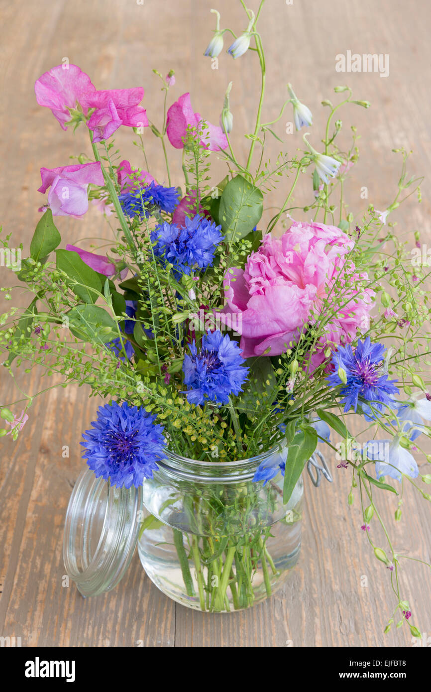 Posy Haufen ziemlich attraktive rosa und blauen Frühlings- und Sommerblumen, einer rustikalen Blumenstrauß Anordnung im Glas Kilner Stall Stockfoto