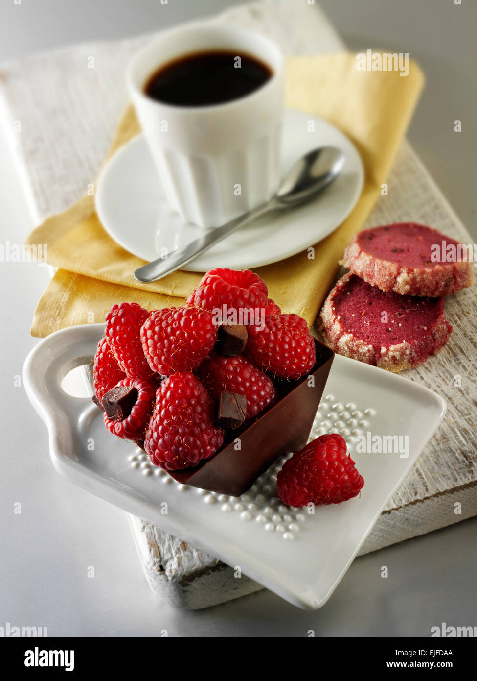 Eine handgemachte Patisserie Spezialität reichen verwöhnenden Schokoladenkuchen gefüllt mit frischen Himbeeren mit Kaffee in einem weißen Tisch Einstellung Stockfoto