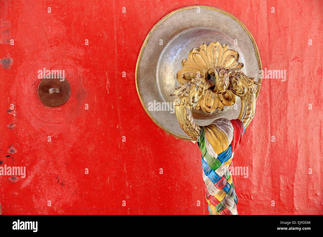 Hölzerne Tür vergoldet Rotguss Türklinke mit Colorist Stoff Zopf hängen. Kelsang Phodrang-alt-Sommerpalast. Norbulingka komplexes Stockfoto