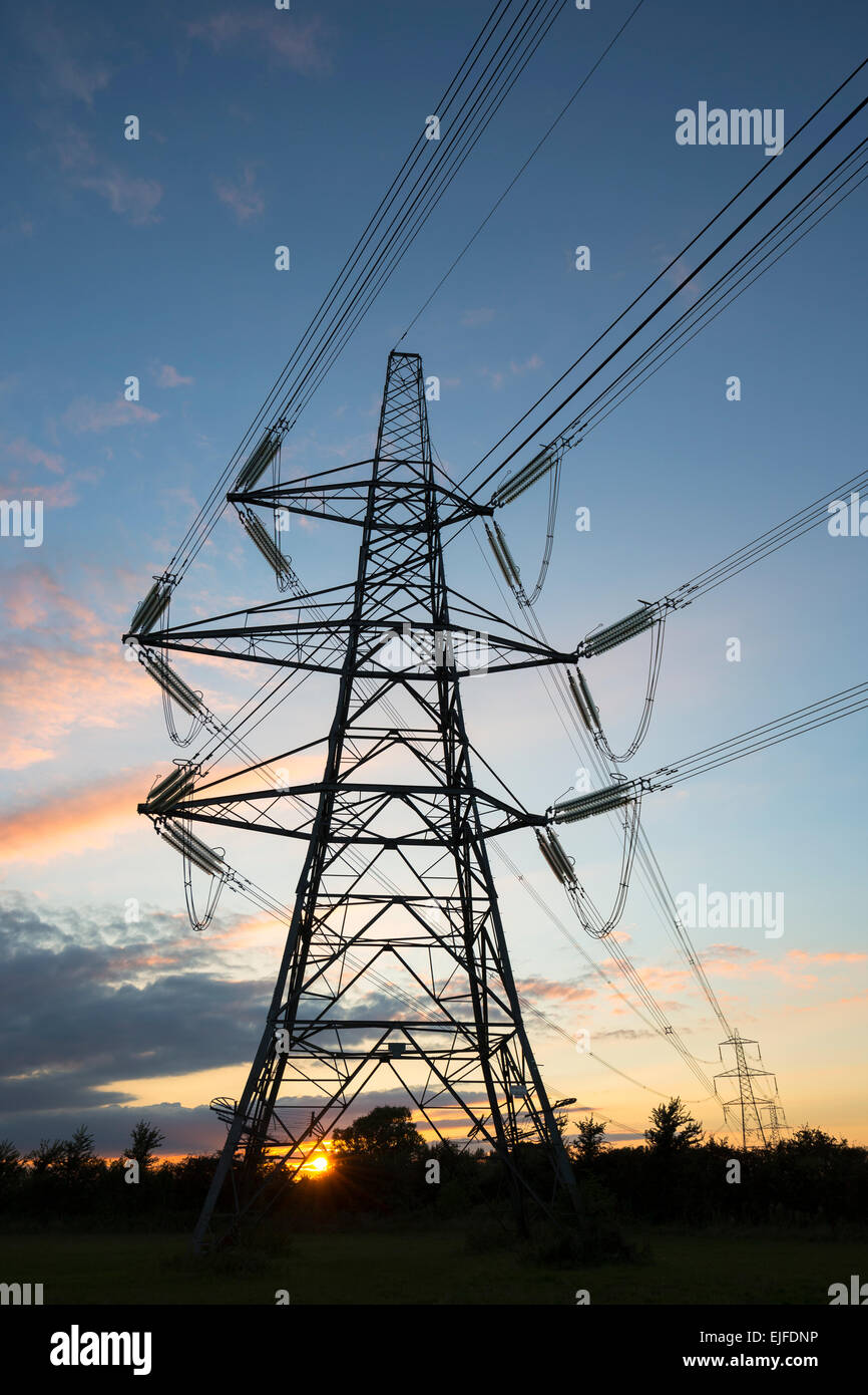 Zwei Formen der Energiestufe - Sonne durch Strommasten die Tupfen Sie die Landschaft bei Sonnenuntergang im Vereinigten Königreich Stockfoto