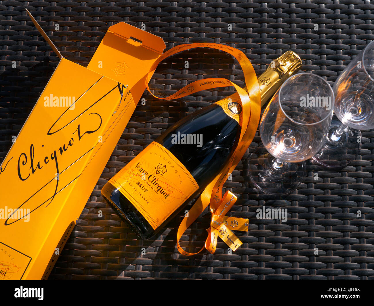 Flasche Veuve Clicquot Champagner Geschenkbox und Gläser auf sonnigen Outdoor-Wicker Tischfläche Stockfoto