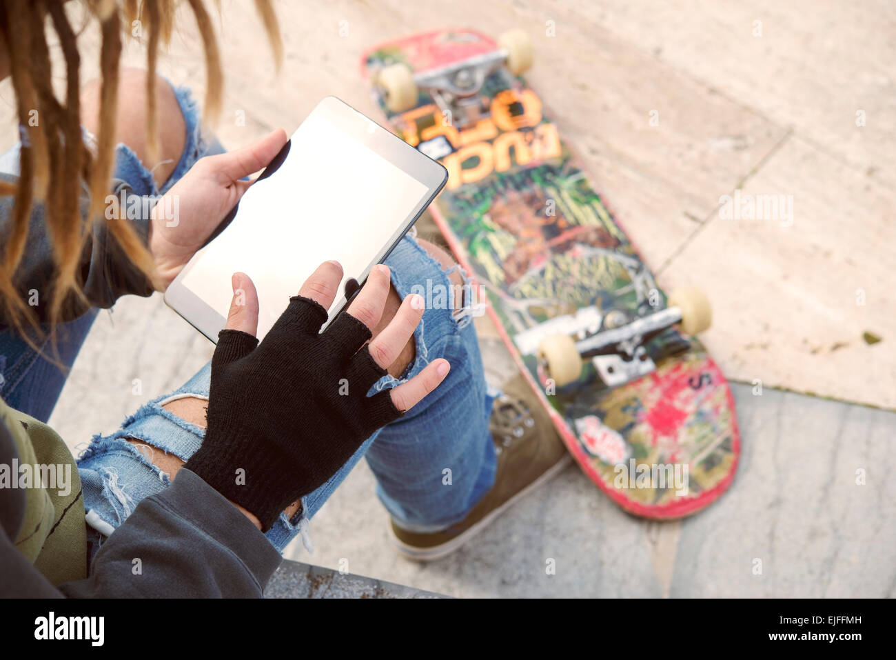 Abgeschnitten Bild männlichen Freiberufler mit Dreadlocks sitzen mit digital-Tablette eingeben warm Nachrichtenfilter angewendet Stockfoto