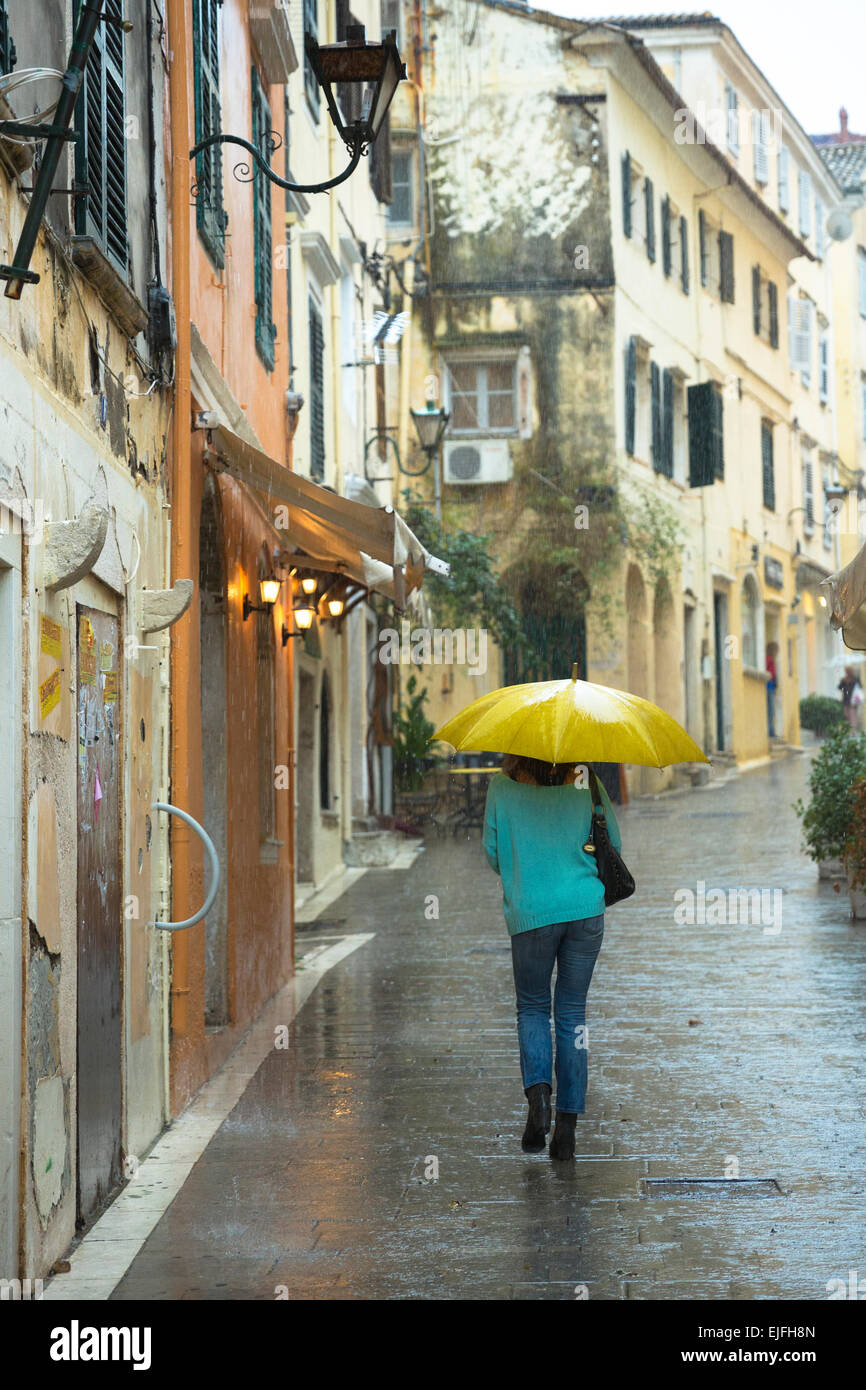 Person zu Fuß mit Regenschirm in regnerischen Tageslichtszene in Kerkyra, Korfu, Griechenland Stockfoto