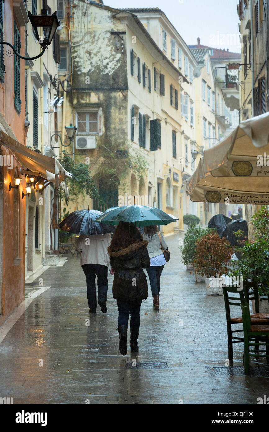 Menschen zu Fuß mit Regenschirm in regnerischen Tageslichtszene in Kerkyra, Korfu, Griechenland Stockfoto
