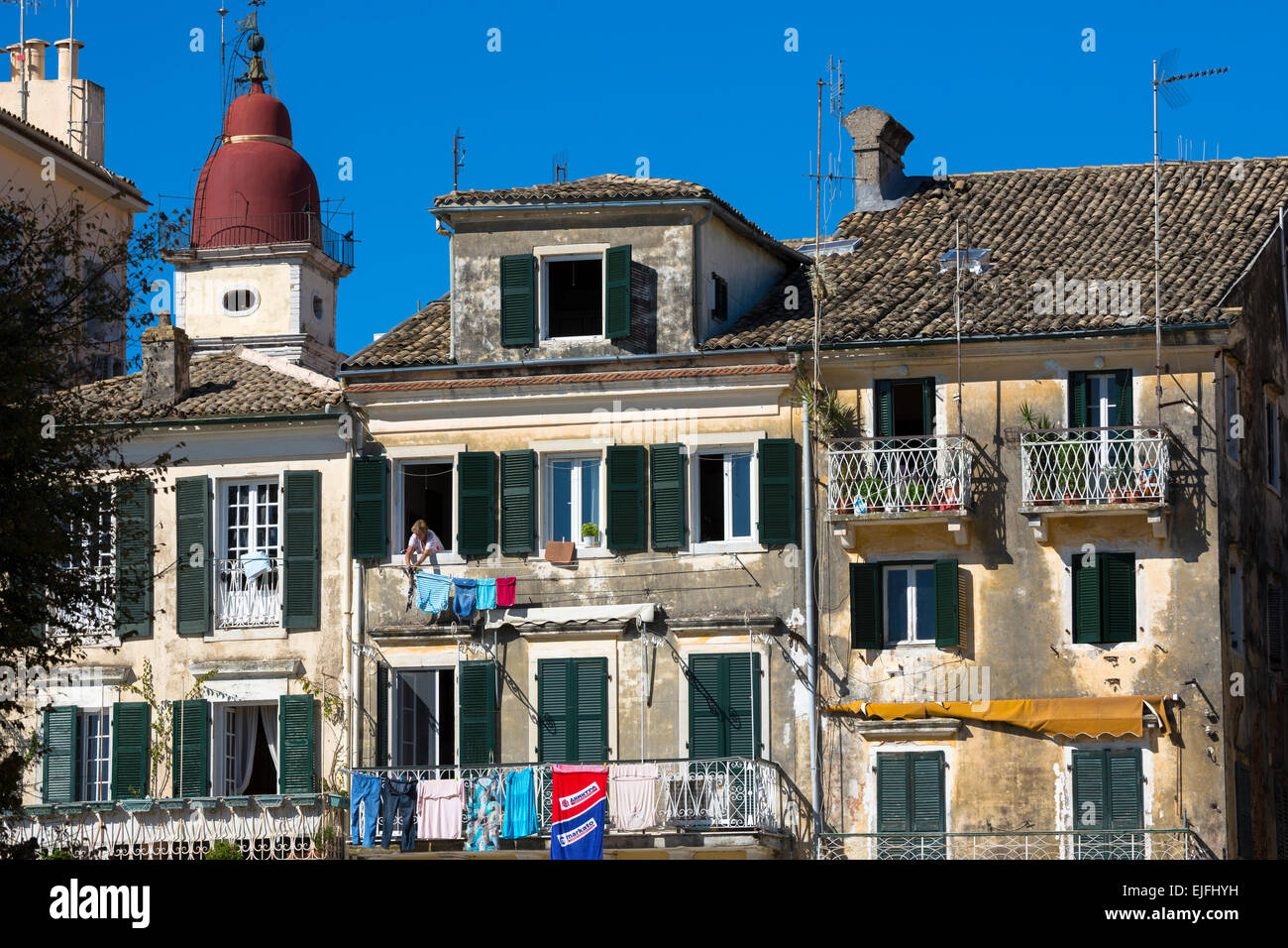 Griechische Frau hängen Wäsche auf Linie vom Fenster des traditionellen Wohnung in Kerkyra, Korfu, Griechenland Stockfoto