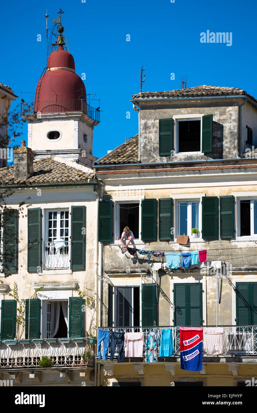 Griechische Frau hängen Wäsche auf Linie vom Fenster des traditionellen Wohnung in Kerkyra, Korfu, Griechenland Stockfoto