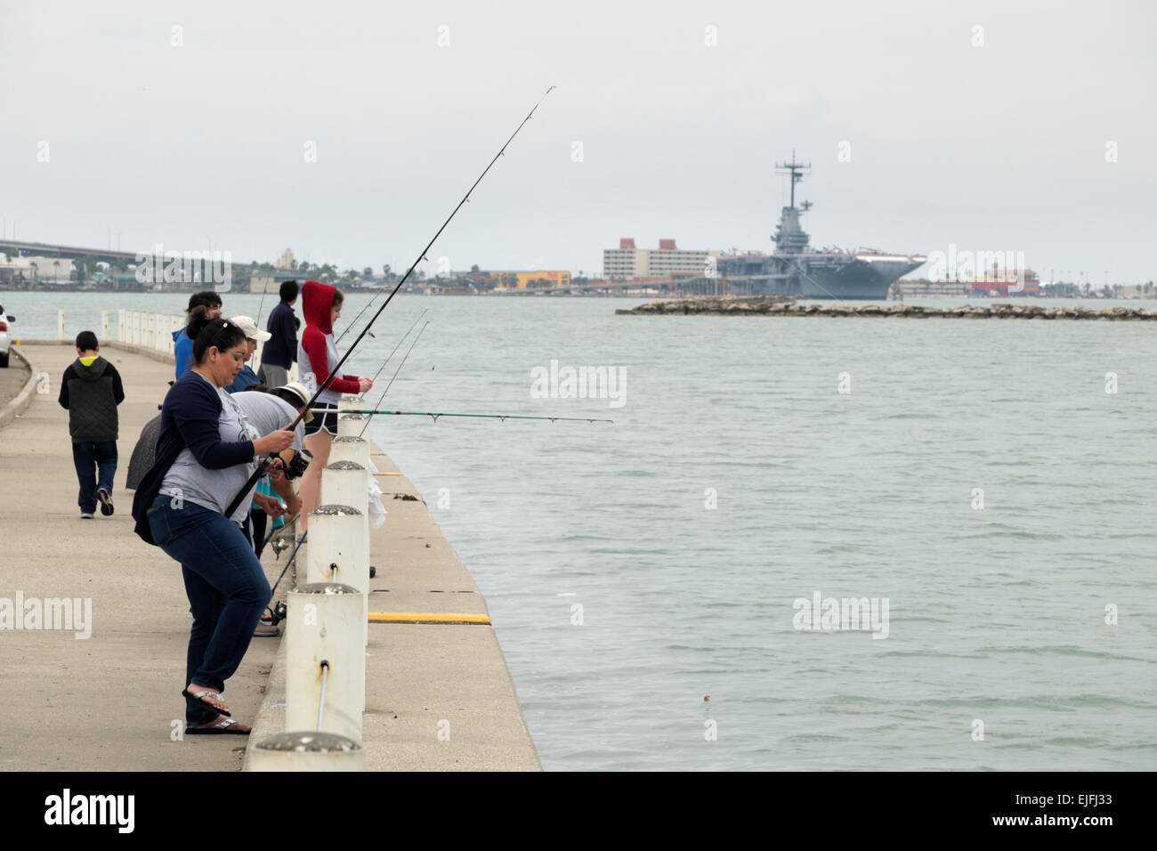 Hispanische Familie Angeln in Corpus Christi Bay mit der U.S.S. Lexington im Hintergrund. Stockfoto