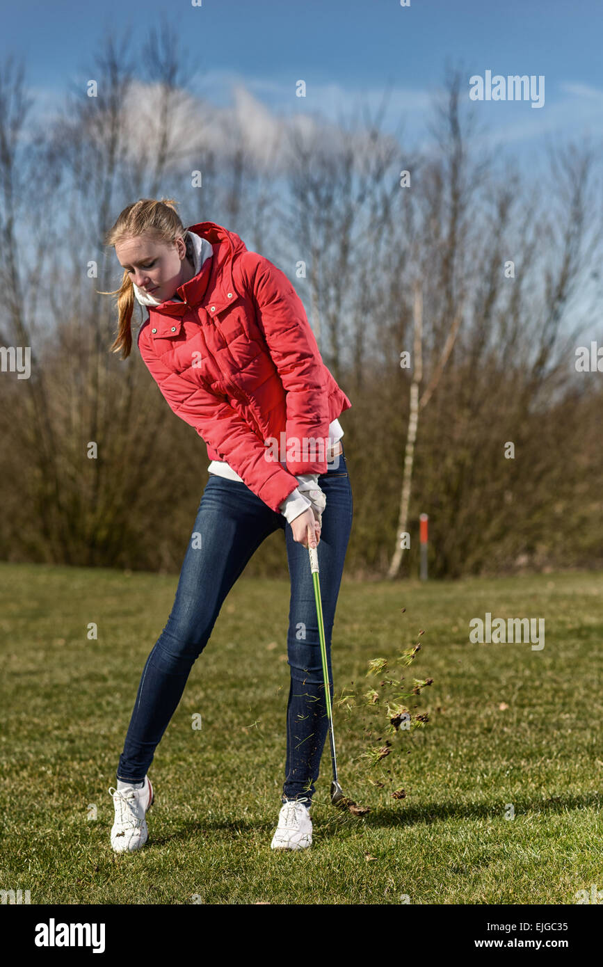 Volle Länge-Schuss eines jungen Golfspielerin, tragen rote Jacke und Skinny-Jeans in der rauen, nur mit einen Ball gespielt Stockfoto