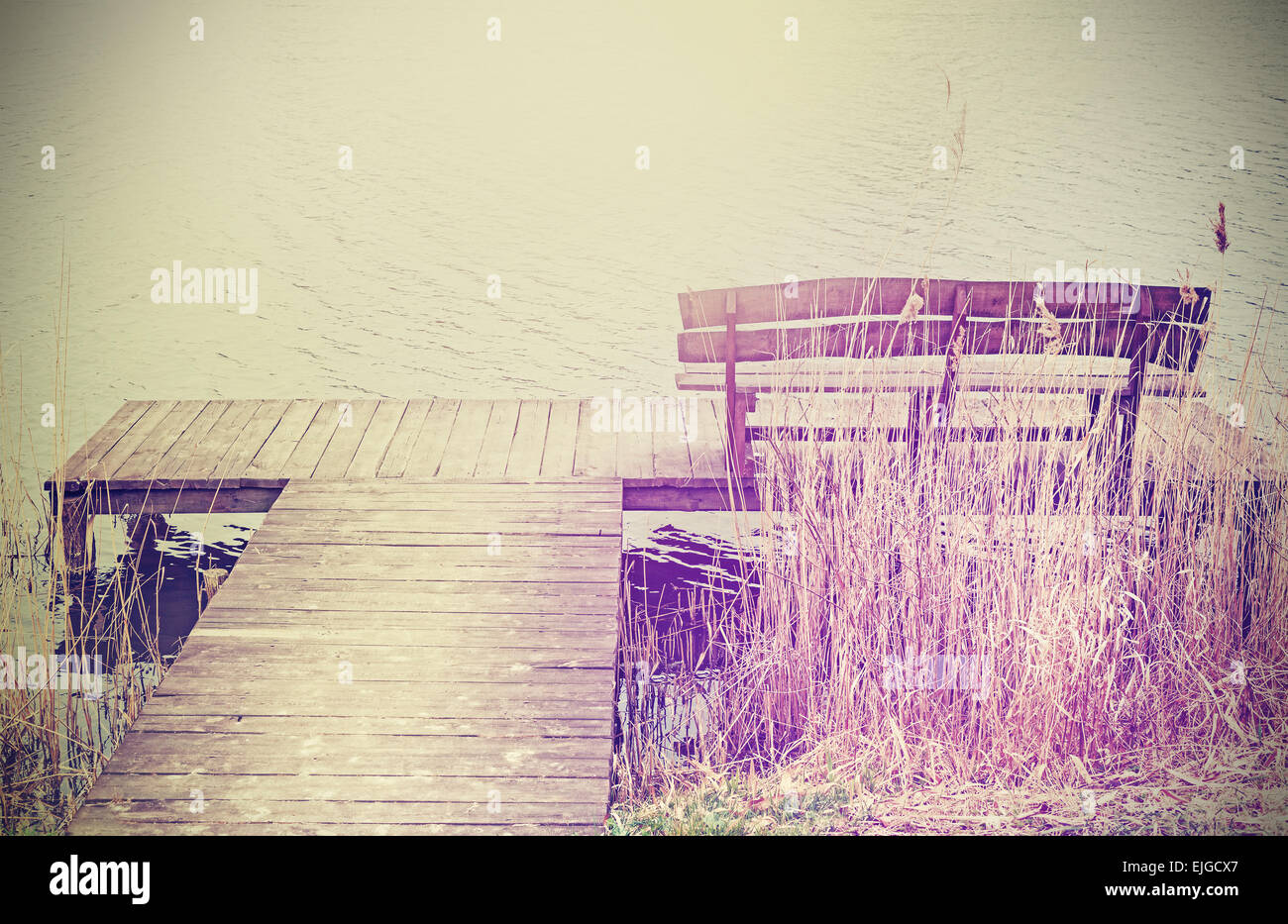Vintage stilisierte Foto von einer Holzbank am See. Stockfoto