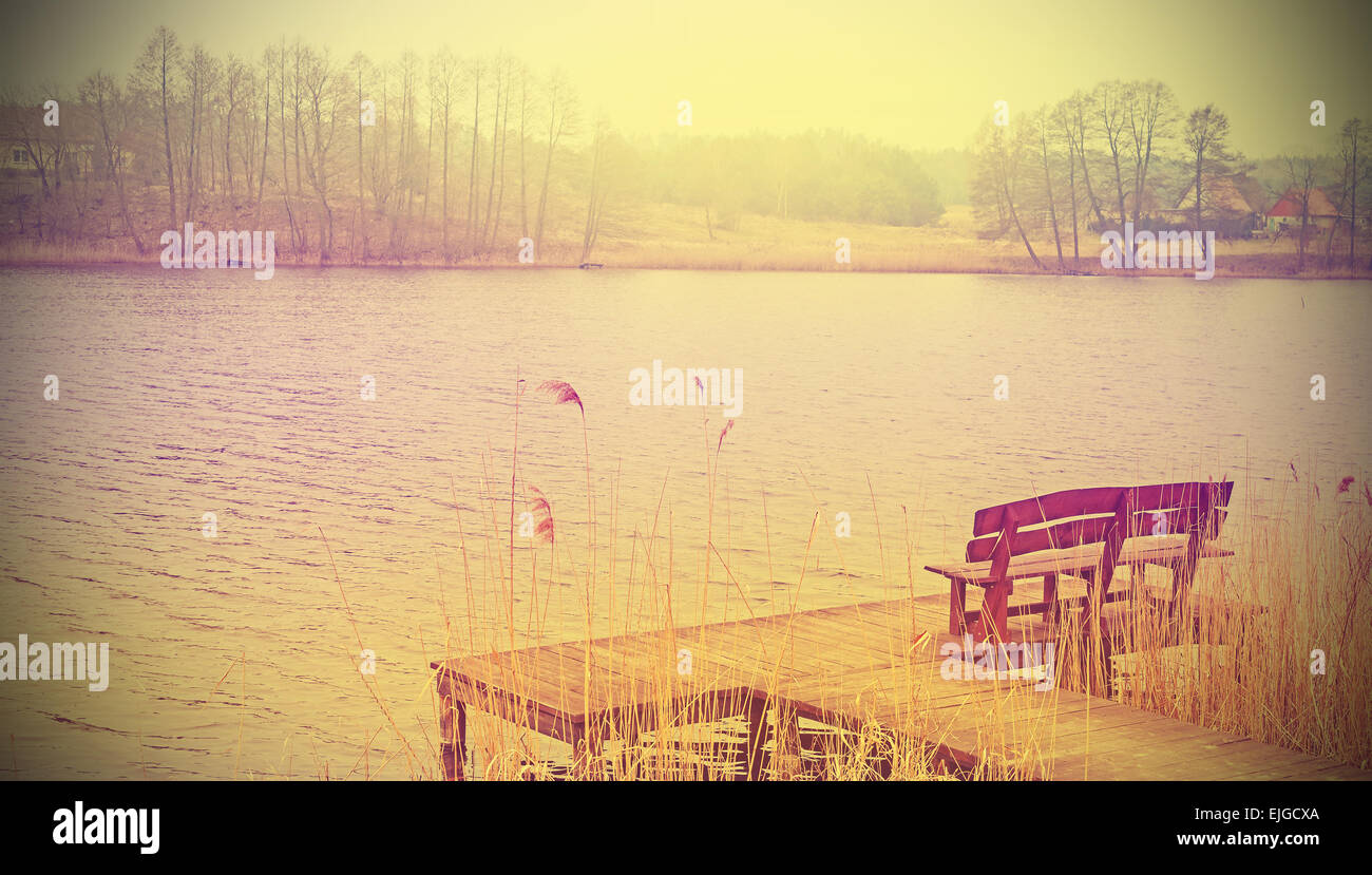 Vintage stilisierte Foto von einer Holzbank am See. Stockfoto