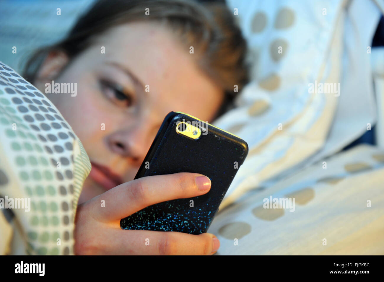 Teenager-Mädchen nutzt ihr Handy nachts im Bett. Stockfoto