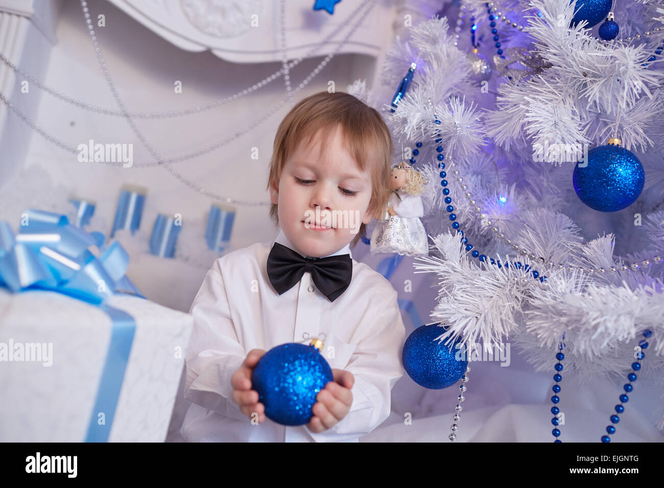 Boy fünf Jahre in Erwartung eines Geschenks, sitzt neben dem Weihnachtsbaum hält einen blauen Ballon Stockfoto