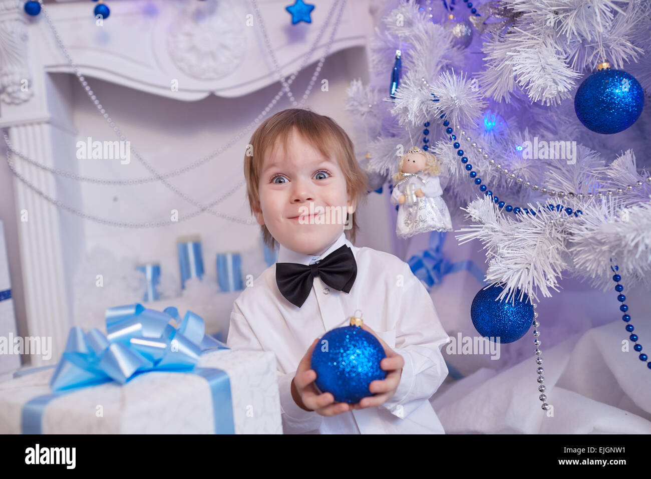 Boy fünf Jahre in Erwartung eines Geschenks, sitzt neben dem Weihnachtsbaum hält einen blauen Ballon Stockfoto