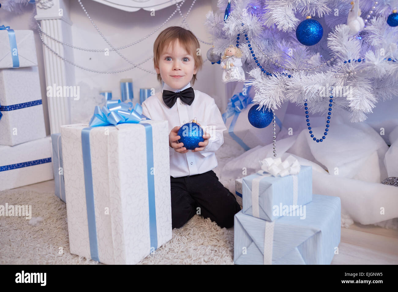 Boy fünf Jahre in Erwartung eines Geschenks, sitzt neben dem Weihnachtsbaum hält einen blauen Ballon Stockfoto