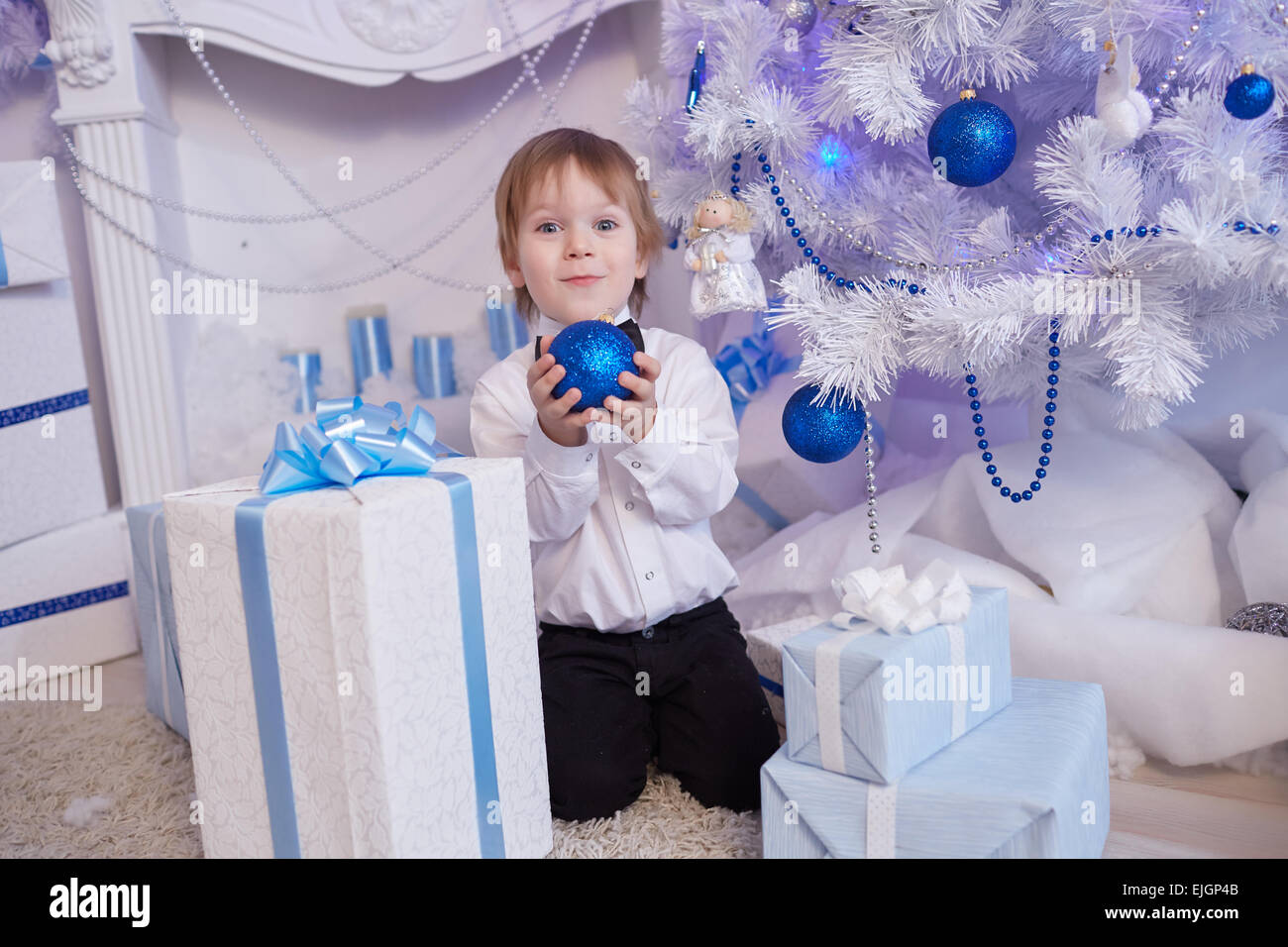 Boy fünf Jahre in Erwartung eines Geschenks, sitzt neben dem Weihnachtsbaum hält einen blauen Ballon Stockfoto