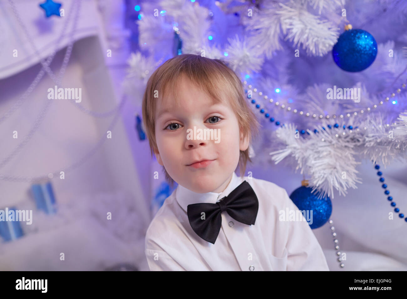 Boy fünf Jahre in Erwartung eines Geschenks, sitzt neben dem Weihnachtsbaum Stockfoto