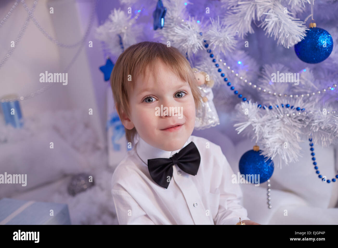 Boy fünf Jahre in Erwartung eines Geschenks, sitzt neben dem Weihnachtsbaum Stockfoto