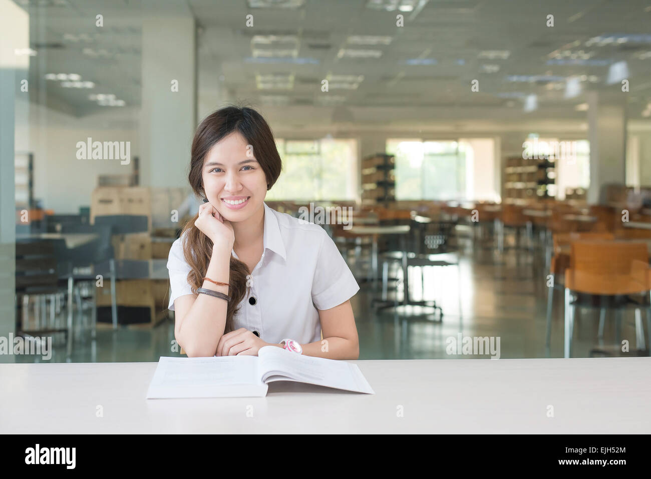 Asiatische Studentin in einheitlichen Lesebuch im Klassenzimmer Stockfoto