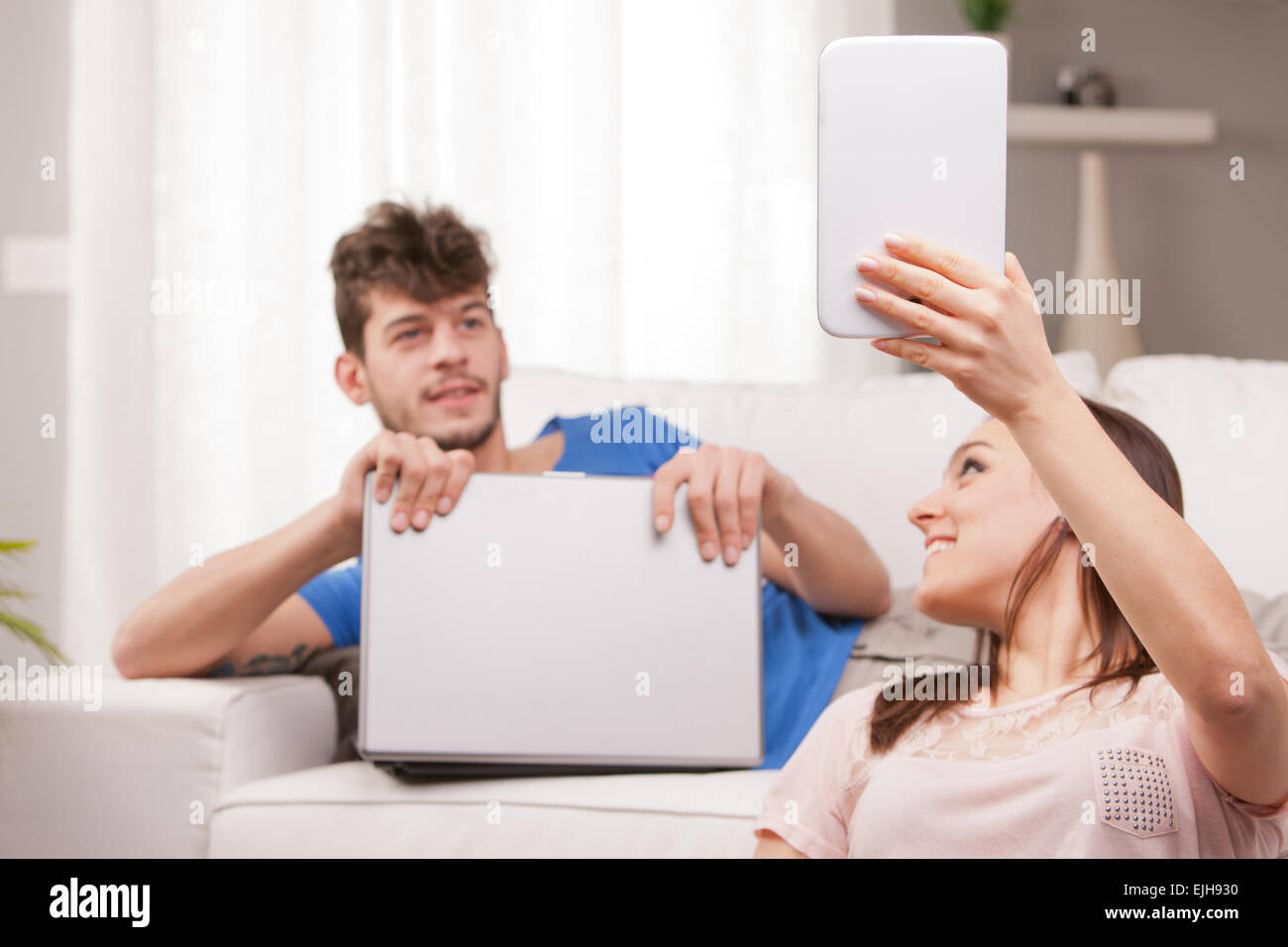 junge Frau, die etwas auf dem Bildschirm ihr Tablet zeigen, während ein junger Mann, gerade dort ein Notebook in seinen Händen hält Stockfoto