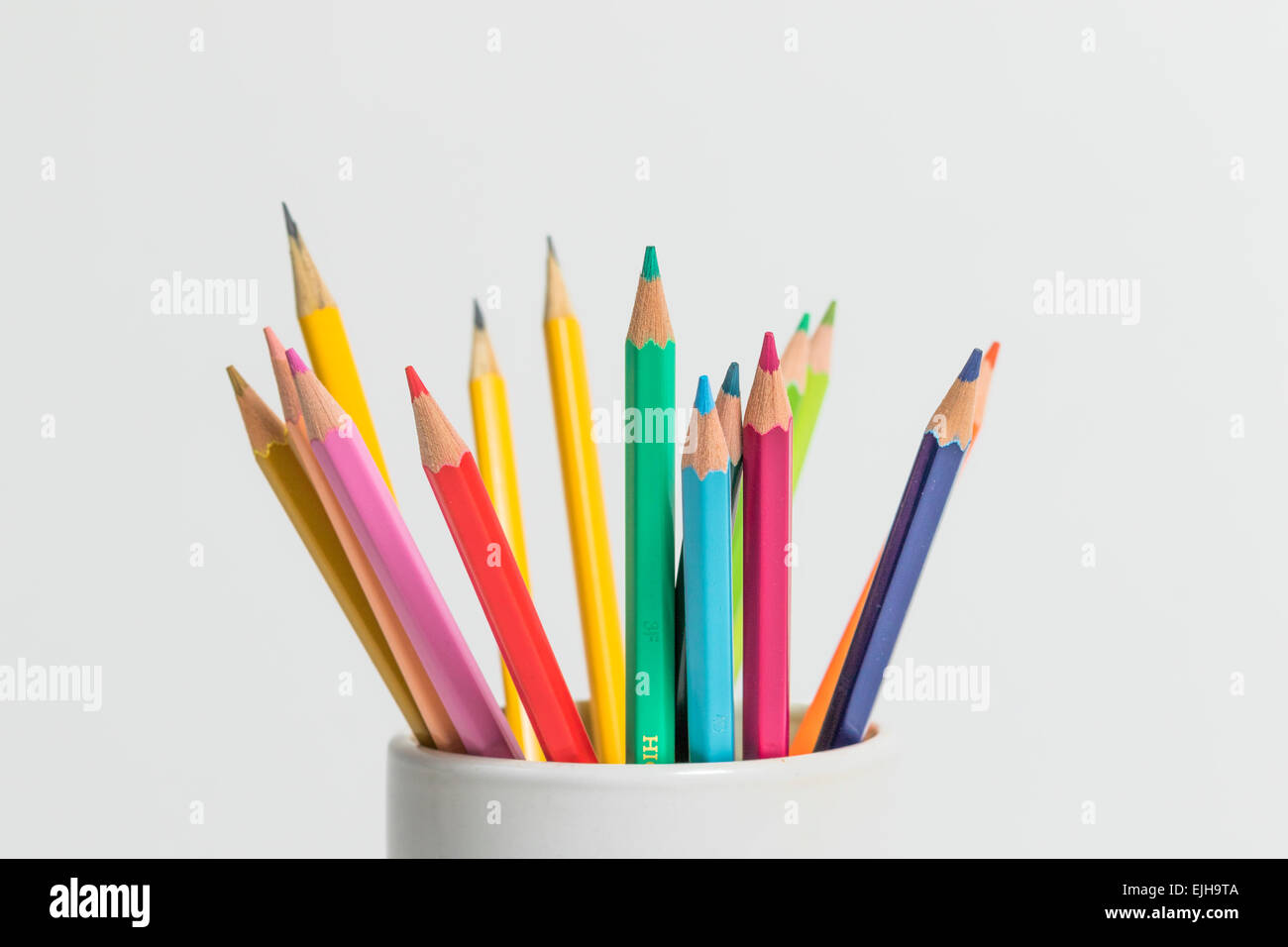 Eine Gruppe von Multi Buntstifte in eine weiße Tasse auf einem isolierten Hintergrund Stockfoto