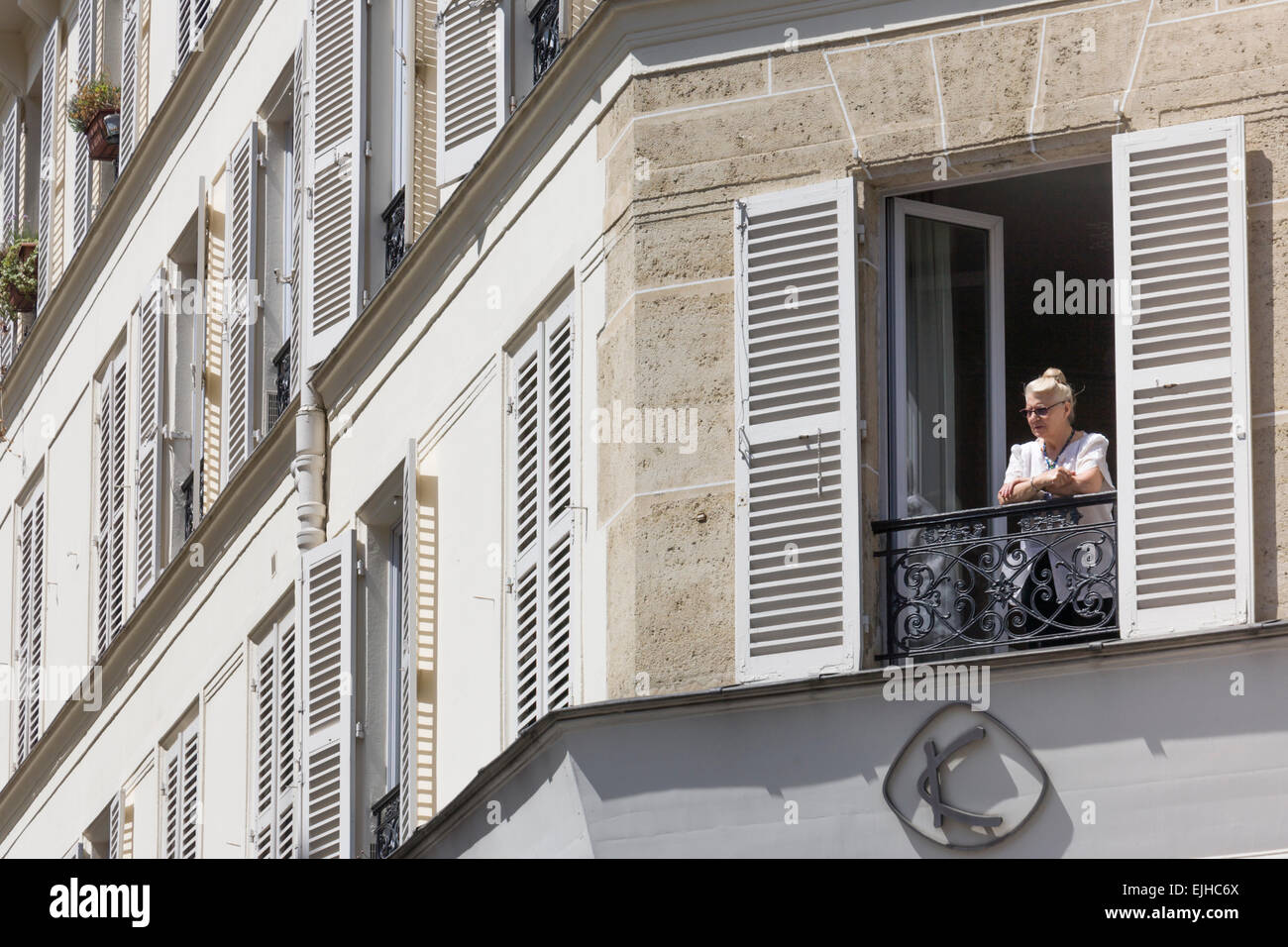 Frau schaut aus Fenster ihrer Wohnung, Paris, Frankreich Stockfoto