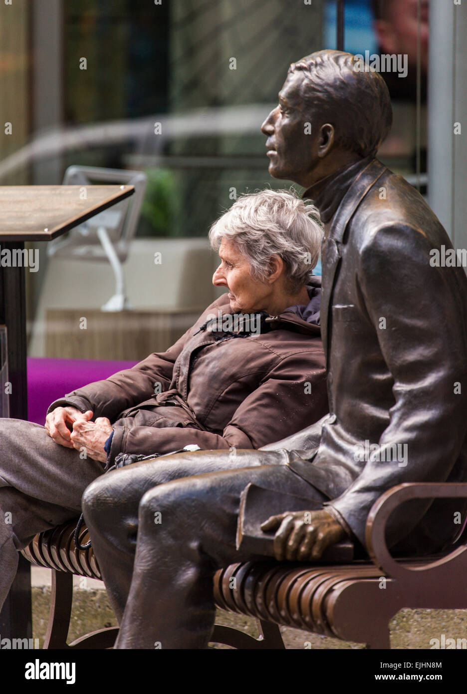 Frau sitzt auf der Bank neben Bronze Statue eines Mannes, New York City, USA Stockfoto