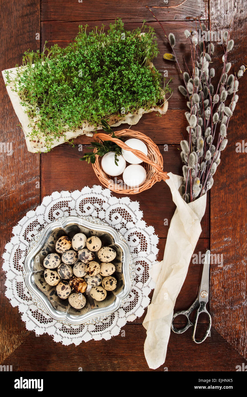 Ostern-Zusammensetzung von Willow Zweige mit Kätzchen, Kresse, Wachteleier in Metall Schale und Ostern Korb mit Eiern, eingestellt auf alten hölzernen Stockfoto