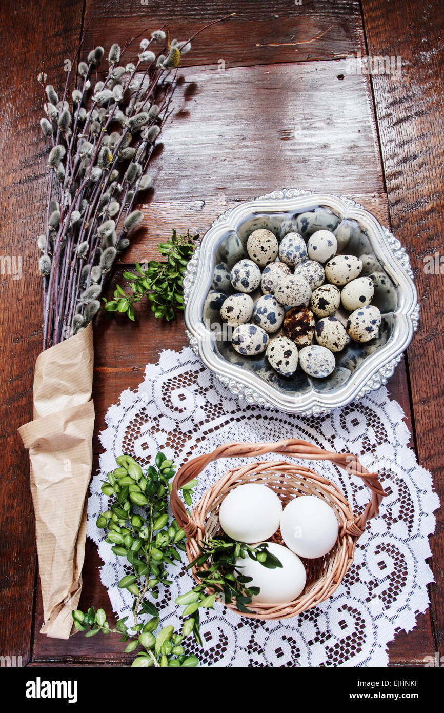 Ostern-Zusammensetzung der Willow Zweige mit Kätzchen, Buchsbaum, Wachteleier in einem Metall-Schale und Osterkorb mit Eiern, auf alten woo Stockfoto