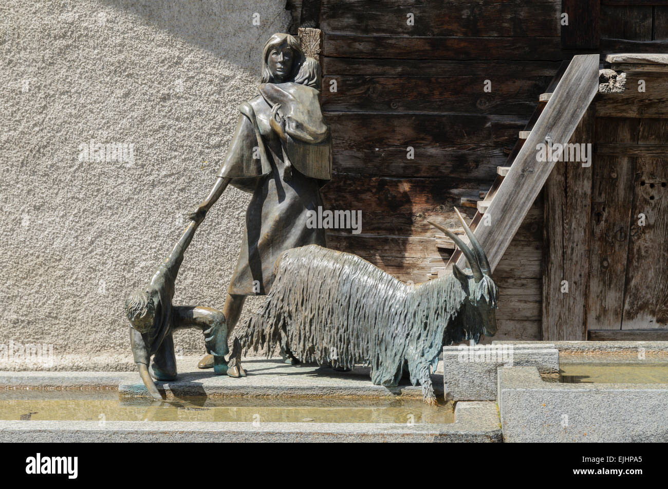 Ein Wasserspiel und die Statue einer Frau mit zwei Kindern und einer Bergziege in Leukerbad, Schweiz Stockfoto