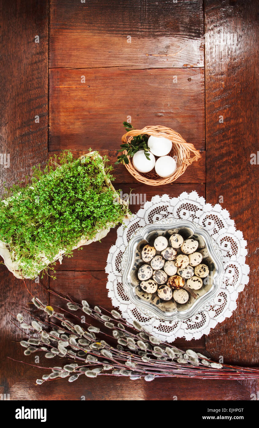 Ostern-Zusammensetzung von Willow Zweige mit Kätzchen, Kresse, Wachteleier in Metall Schale und Ostern Korb mit Eiern, am Tisch Stockfoto