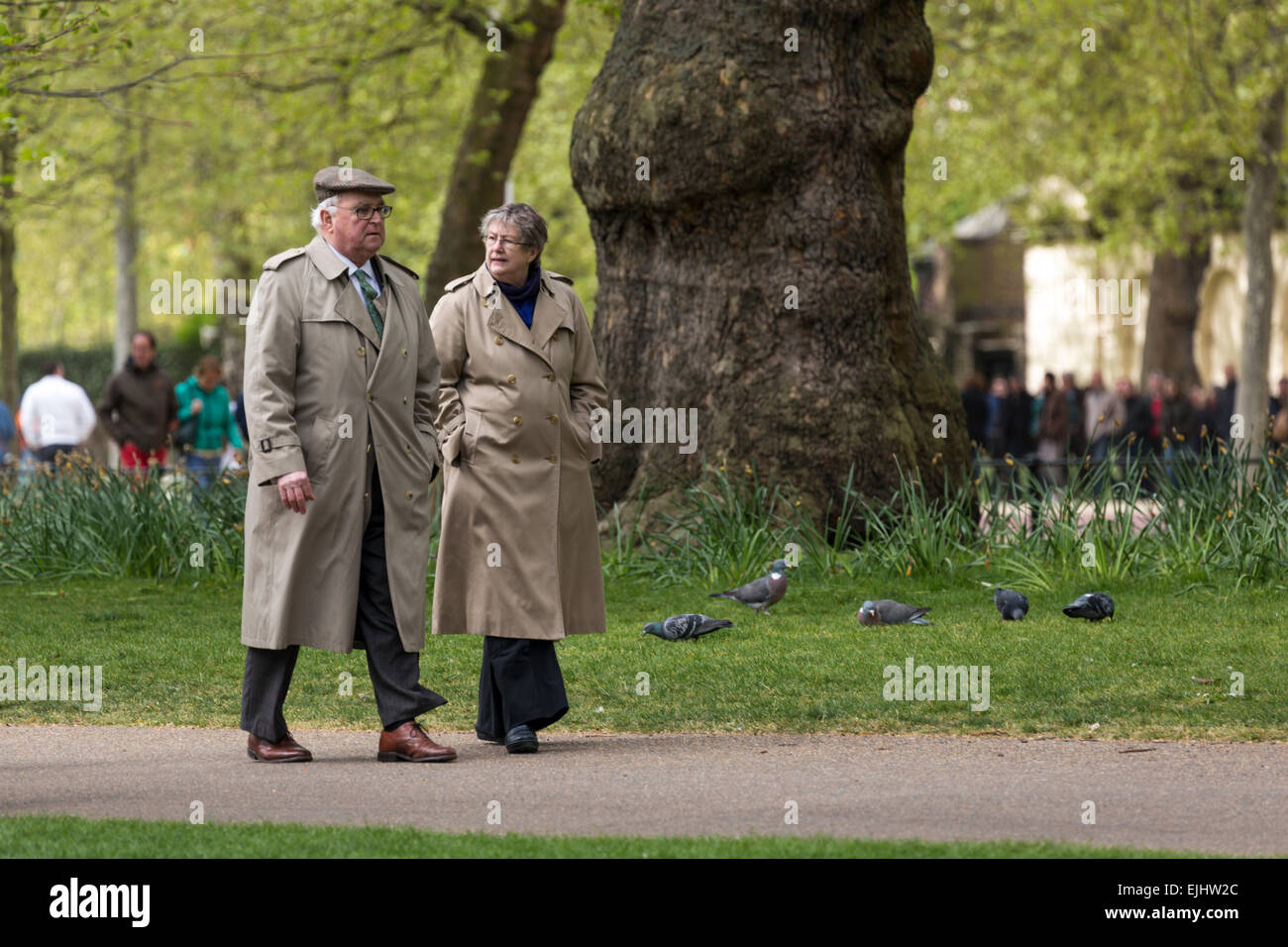 Ältere Mann und Frau einen Spaziergang im St. James Park in intelligente Regenmäntel, London, England Stockfoto