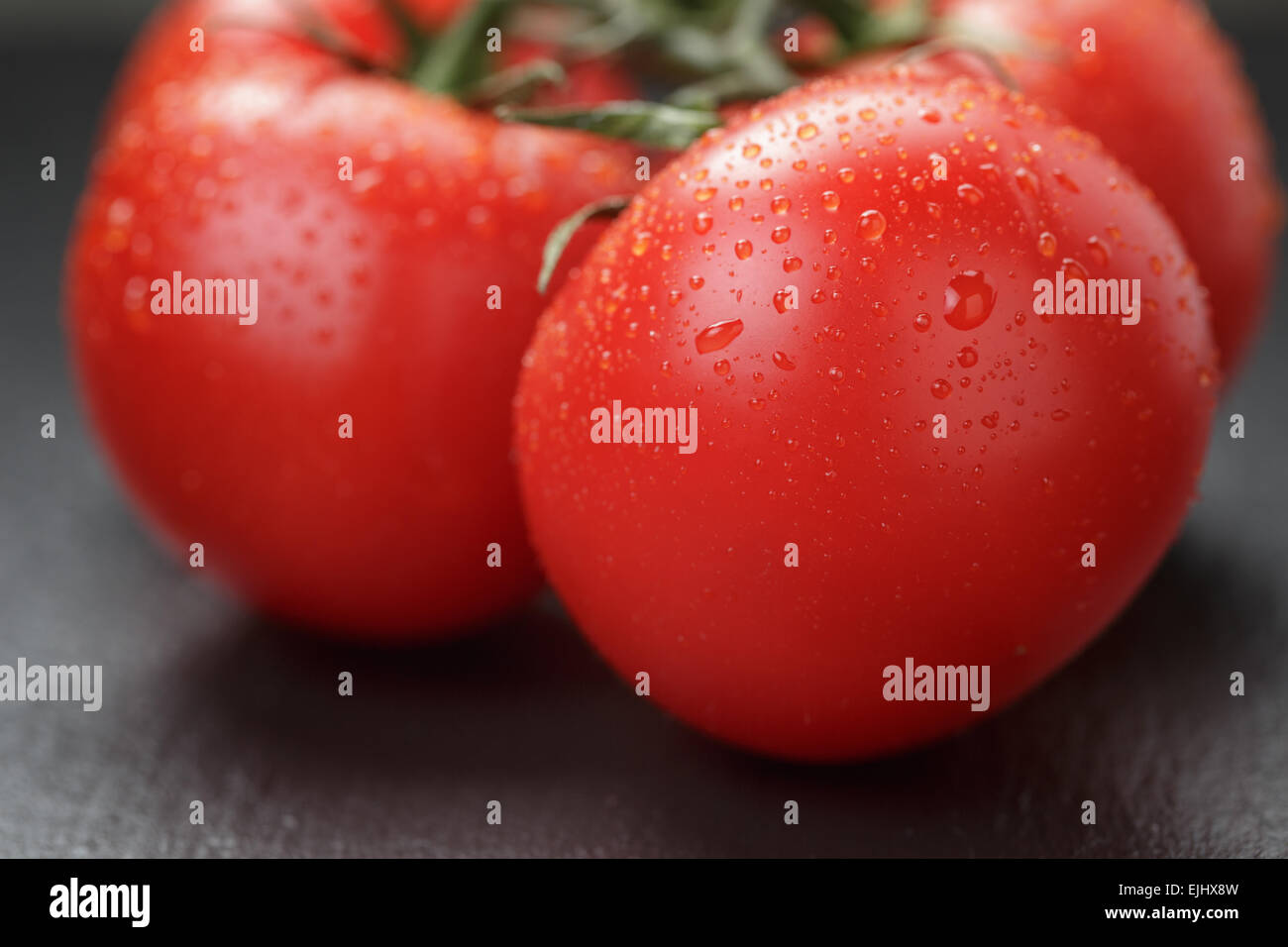 Reife gewaschenen Tomaten an Rebstöcken auf Schiefer Hintergrund Stockfoto