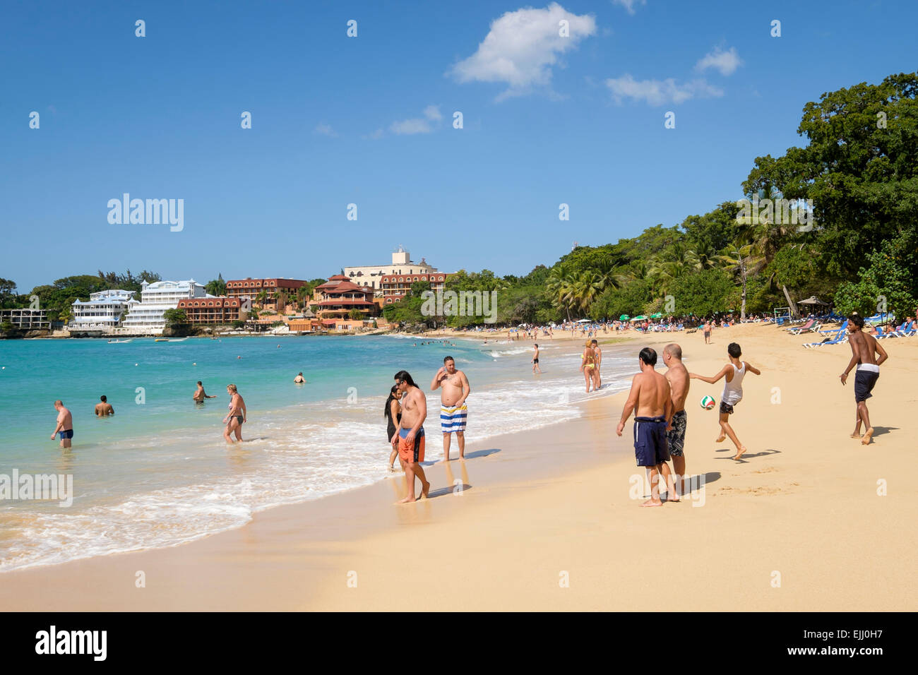 Touristen und Einheimische an einem Sandstrand am Atlantik im Ferienort Sosua, Dominikanische Republik, Karibik Stockfoto
