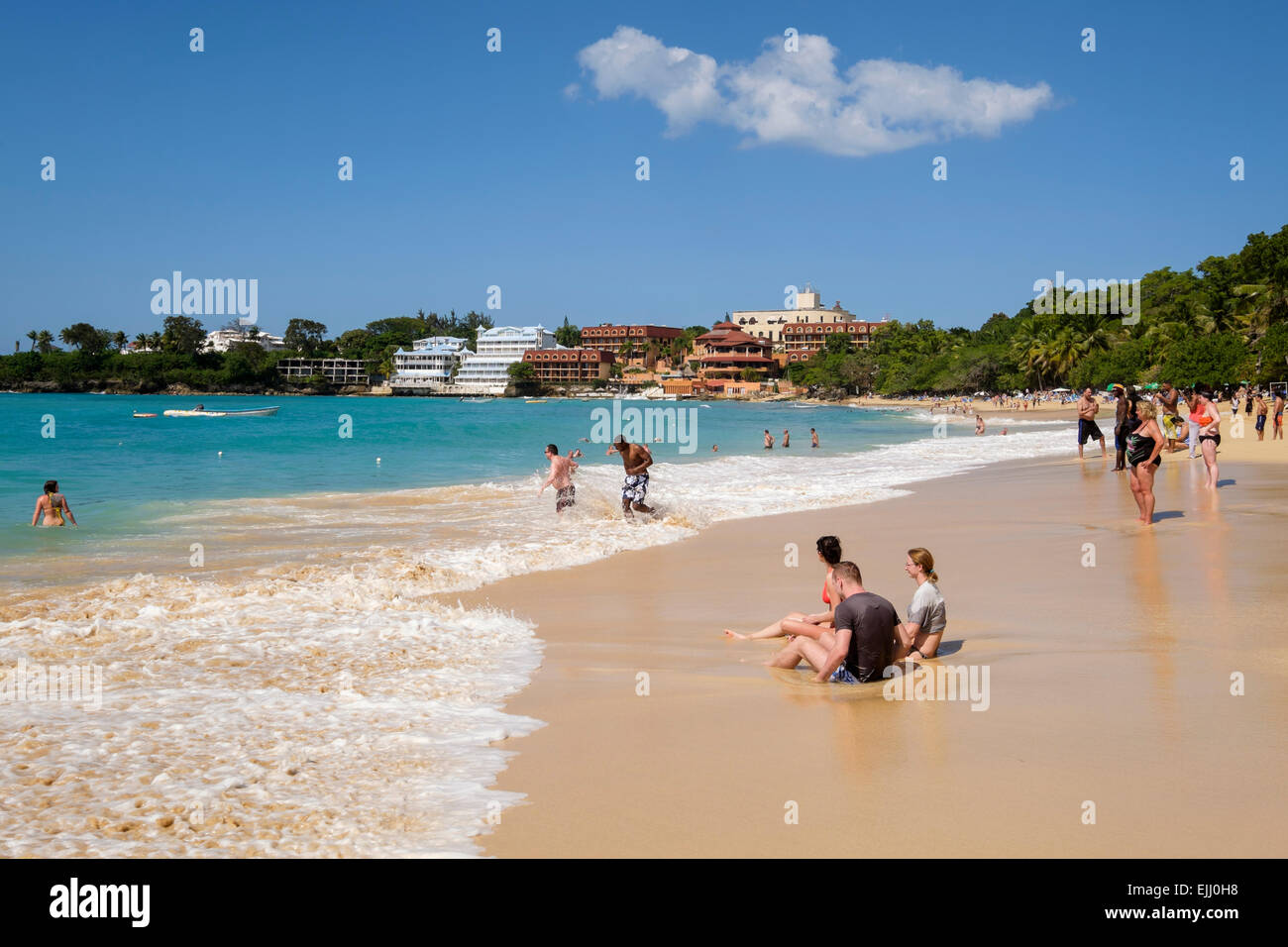Touristen und Einheimische an einem Sandstrand am Atlantik im Ferienort Sosua, Dominikanische Republik, Karibik Stockfoto