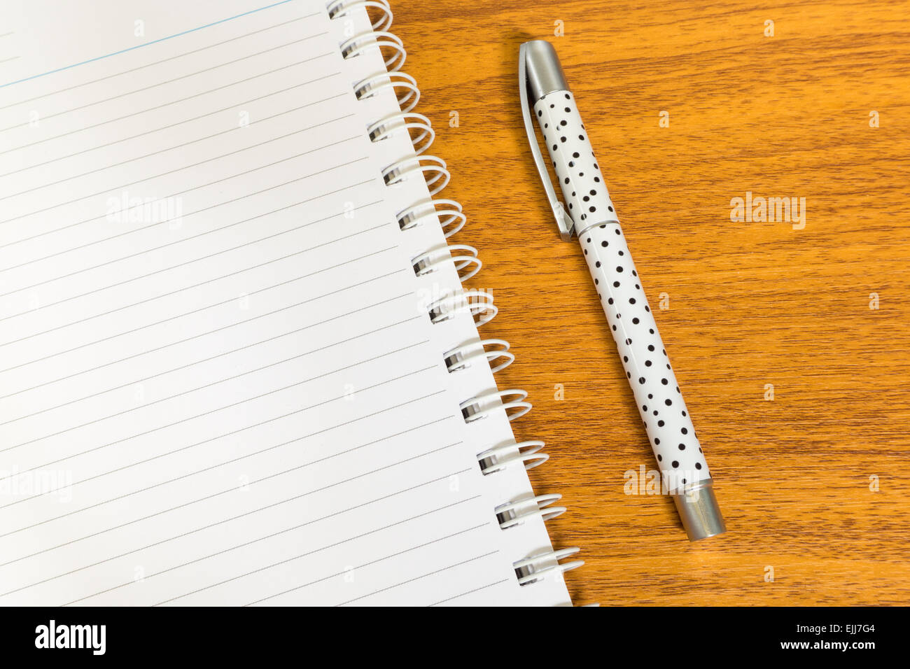 Weißer Punkt Stift mit offenen weißen Notebook mit Linie auf Holztisch Stockfoto