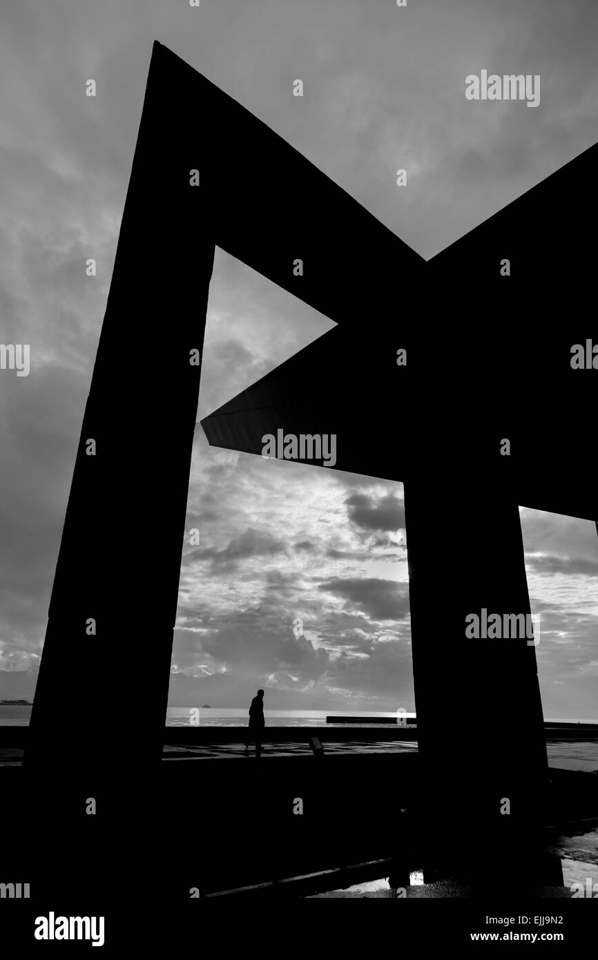 Man spaziert unter Silhouette der Menschenrechte Monument in der Nähe von Meer mit bewölkten Hintergrund in Karsiyaka Izmir, Türkei Stockfoto