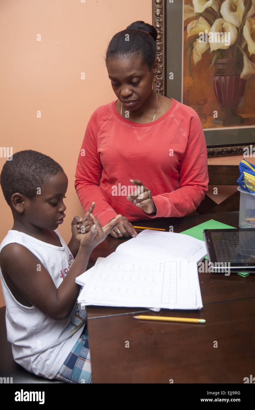 Mama arbeitet mit ihrem jüngsten Sohn mit Mathe-Hausaufgaben. Stockfoto