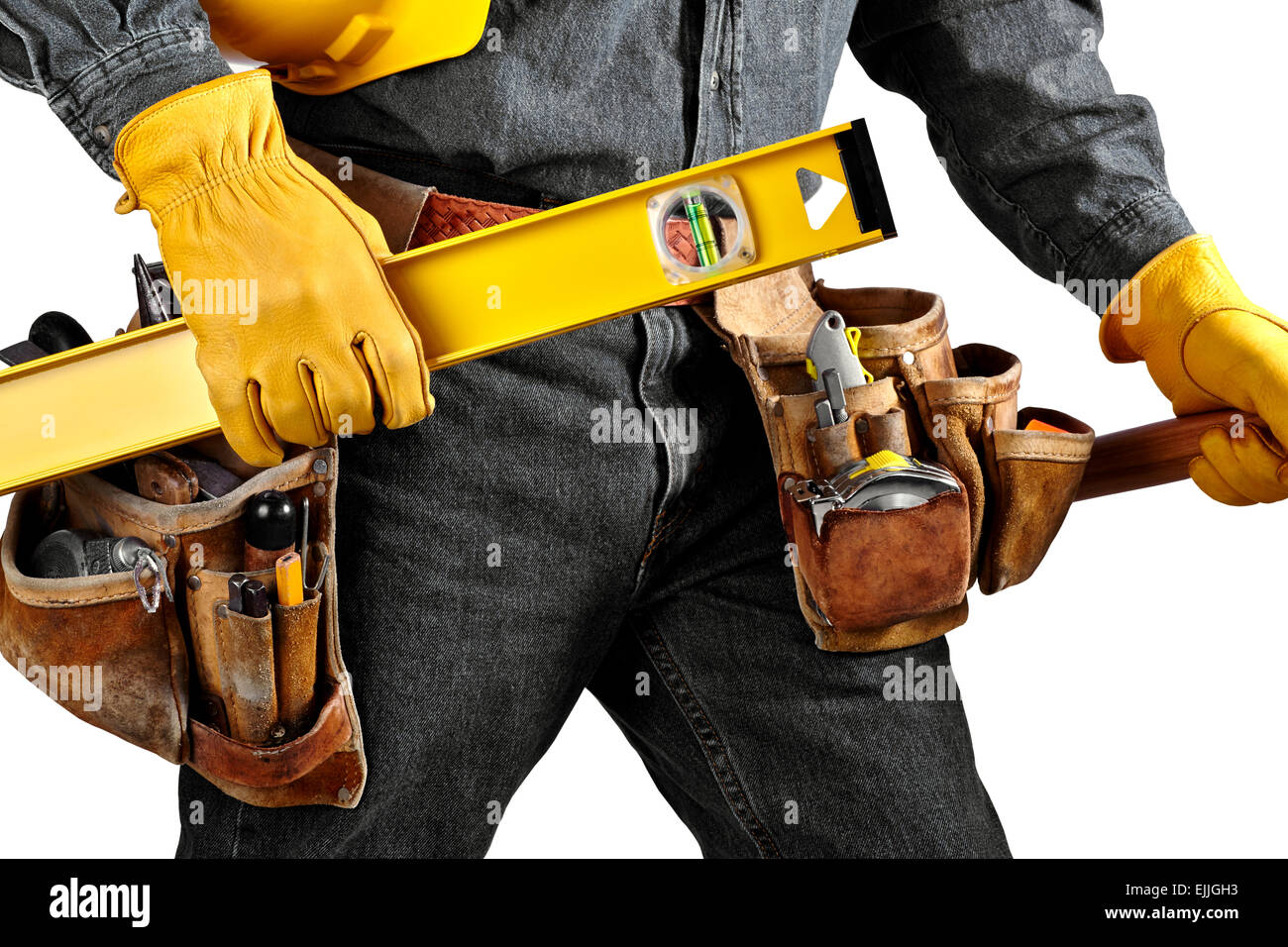 Mann in schwarzem Denim tragen verwendet Werkzeuggürtel gefüllt mit Tischlerwerkzeuge trägt eine gelbe Ebene, Helm und hammer Stockfoto