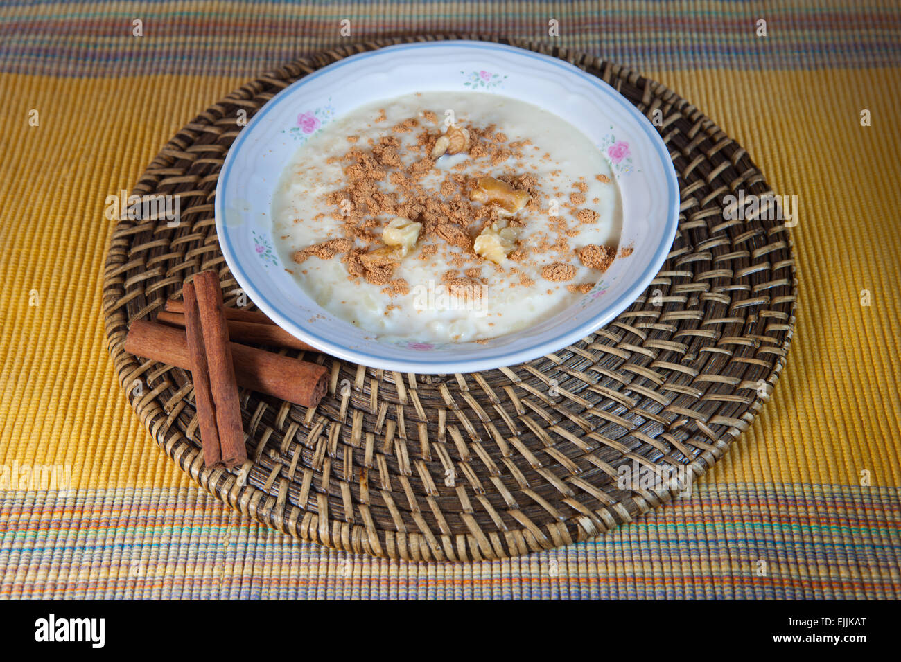 Köstliche hausgemachte Reis mit Milch und Zimt in einer Schüssel China über Naturfaser Tischset Stockfoto