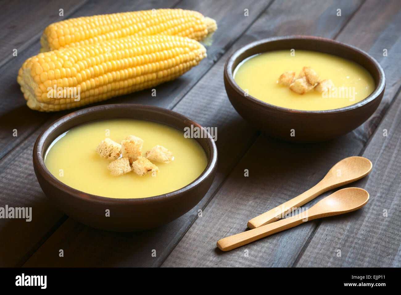 Zwei Schüsseln mit Creme von Mais-Suppe mit Croutons obenauf, fotografiert auf dunklem Holz mit natürlichem Licht (Tiefenschärfe) Stockfoto